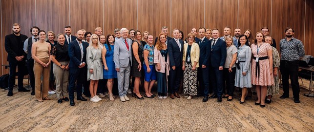 Group photo of around 40 participants in front of a wooden wall