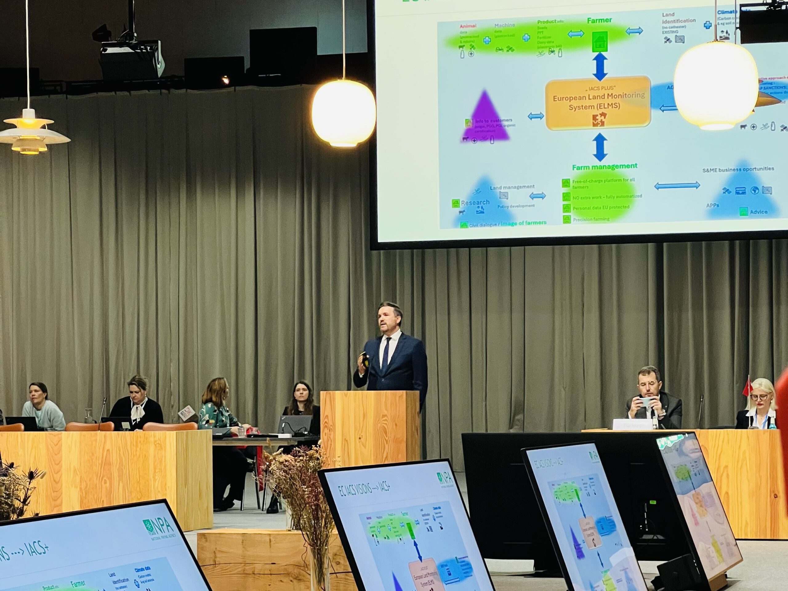 Photo of a presentation with several screens in a conference room